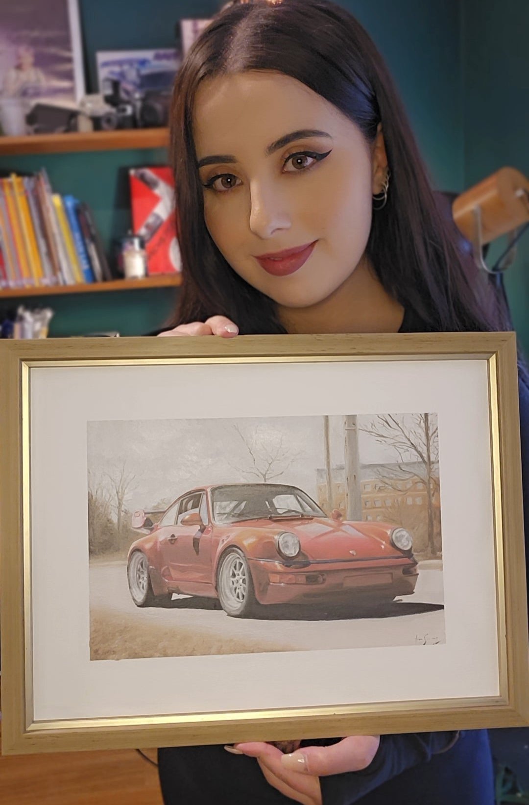 Tiana Kaiserfeld proudly holds her detailed painting of a classic Porsche, showcasing her skill in automotive art and realism.